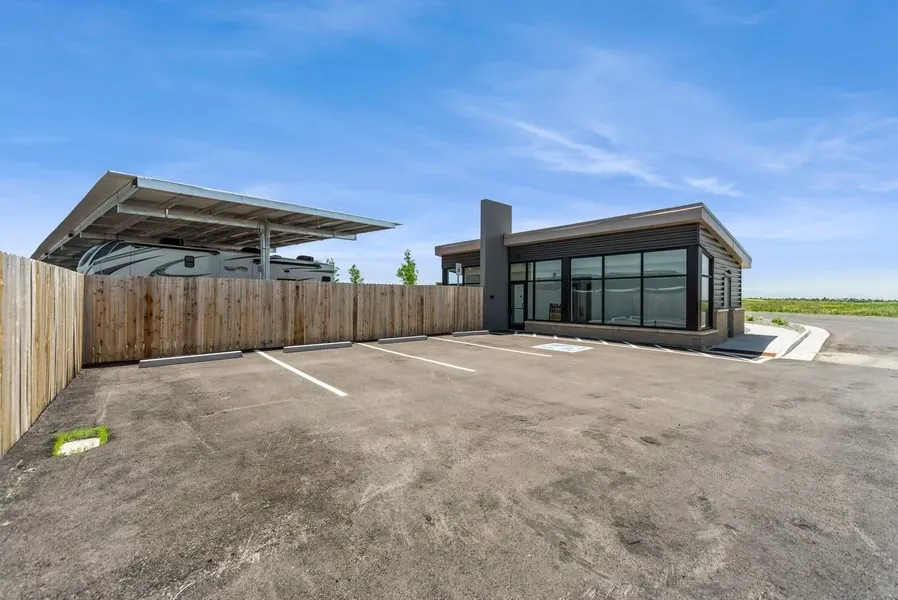 Parking spaces in front of the security office for a RV parking lot. A RV can be just beyond the fence.