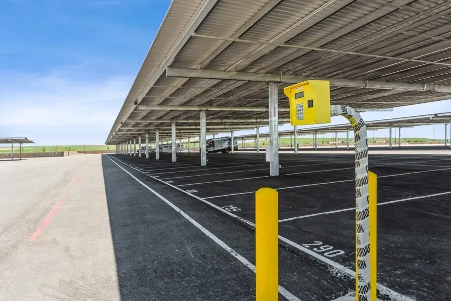 A shot of mostly empty covered parking spaces. A yellow security box is in the foreground