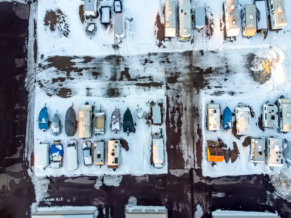 An aerial view of snow covered boats and RVs in a storage lot.