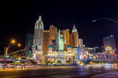 The Las Vegas Strip lit up at night, with buildings in various architectural styles and a smaller scaled version of the...