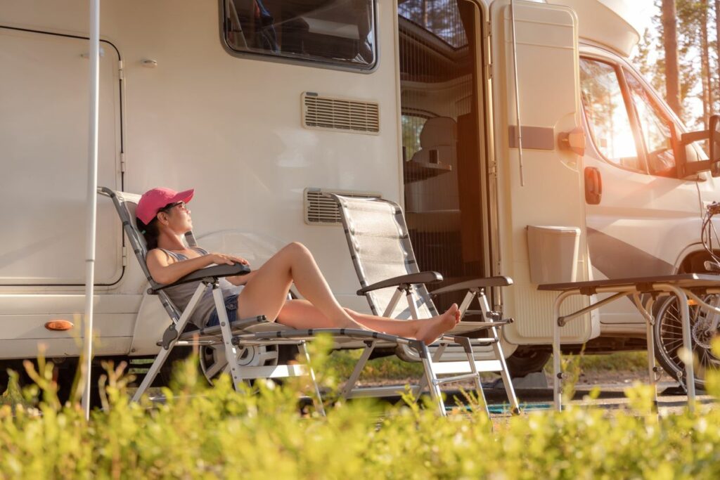 A person relaxing in a foldable chair beside their RV.