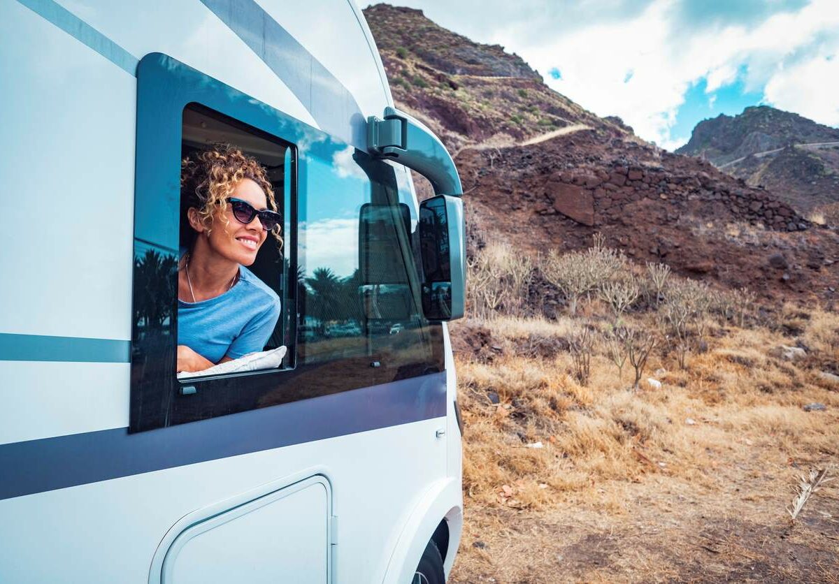 Woman smiling out of RV window.