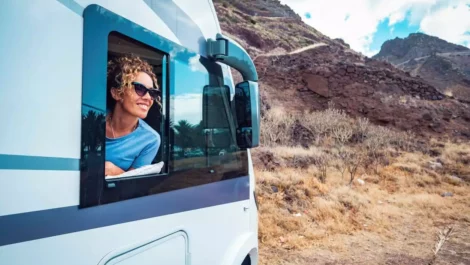 Woman smiling out of RV window.