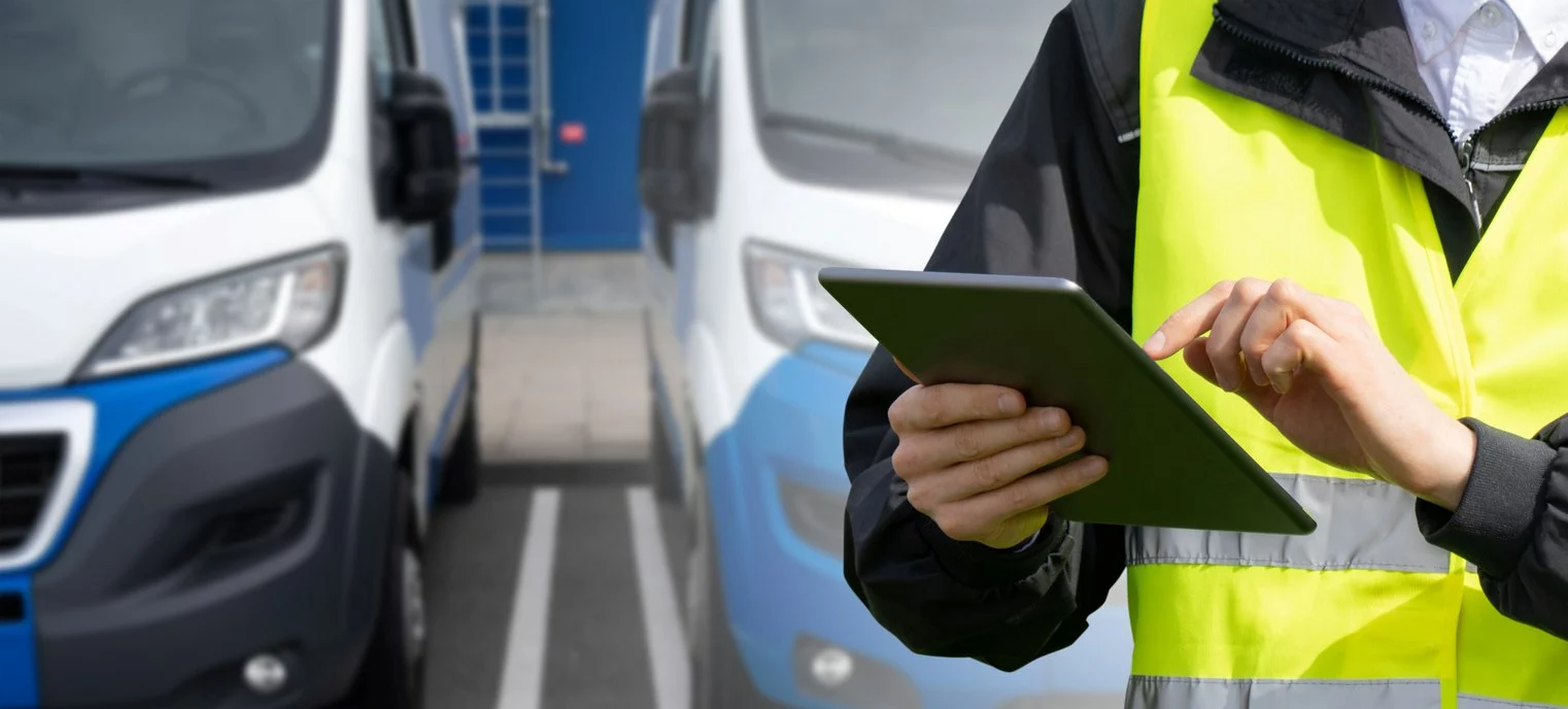 Fleet manager with a digital tablet in front of vans. 