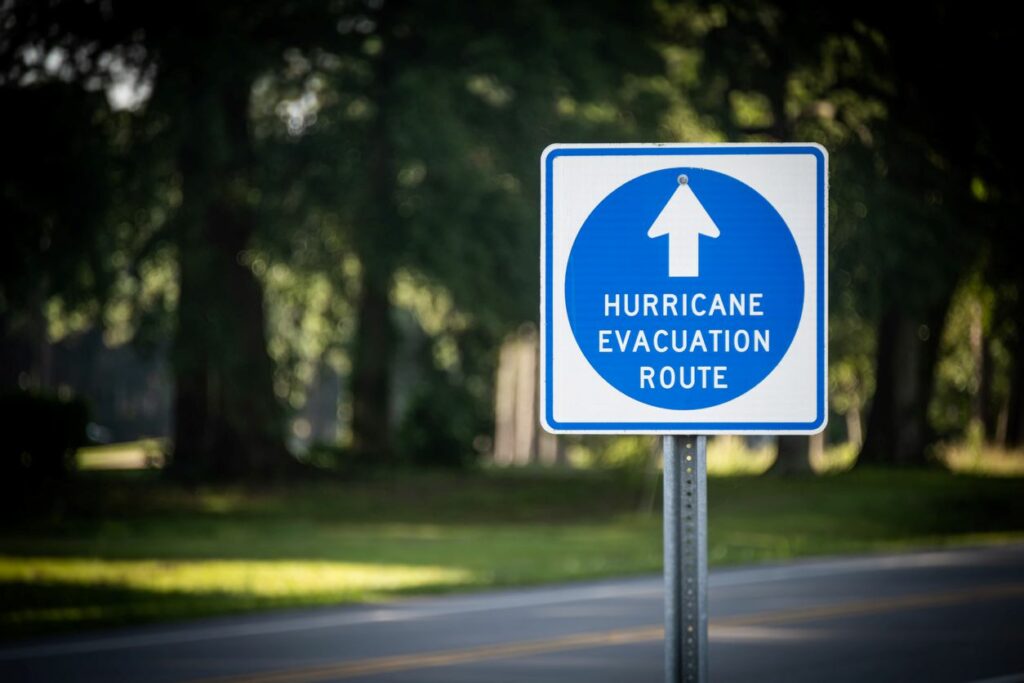 A road sign reading “Hurricane Evacuation Route” on a tree-lined street. 