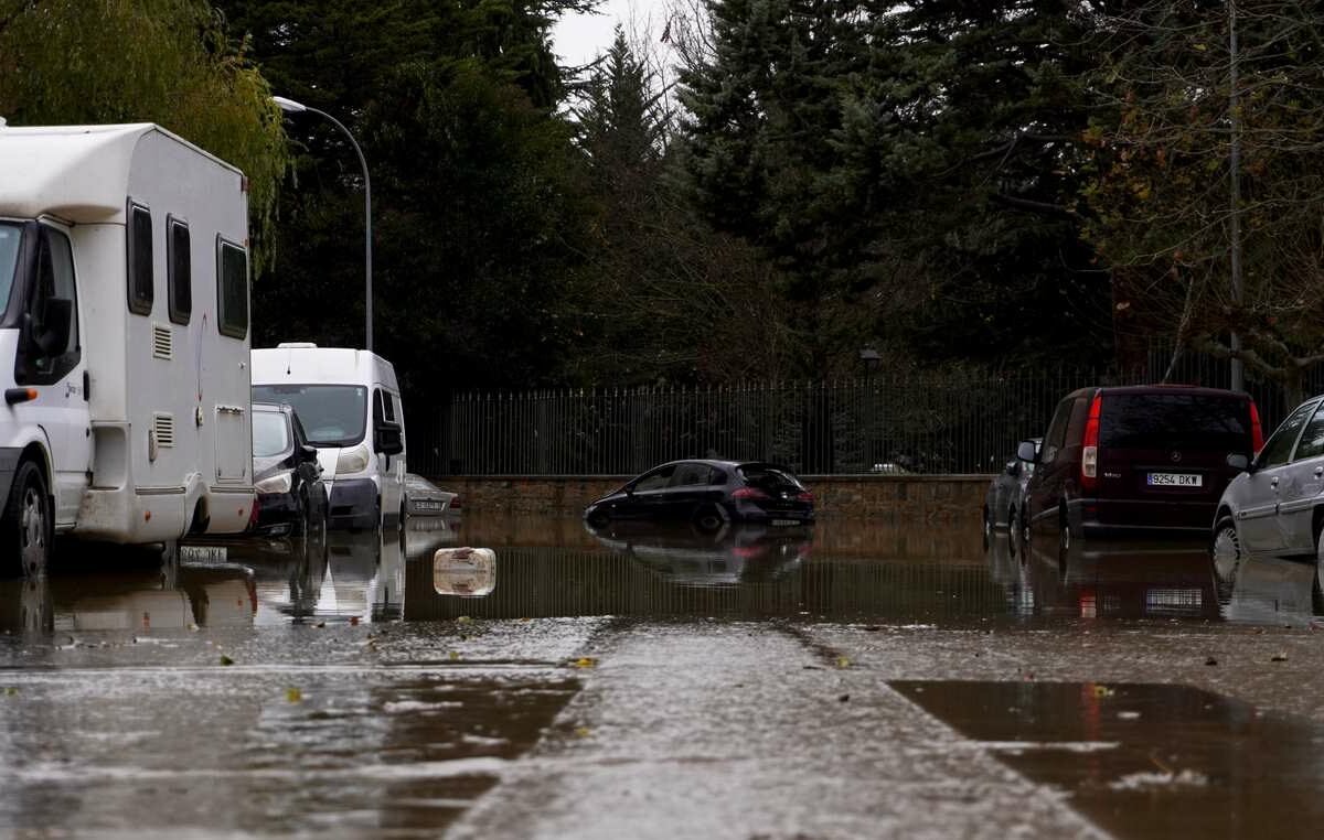 RVs and cars on a street with flooding roads.