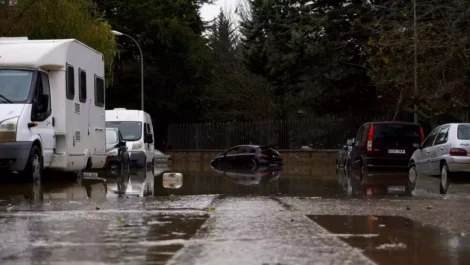 RVs and cars on a street with flooding roads.