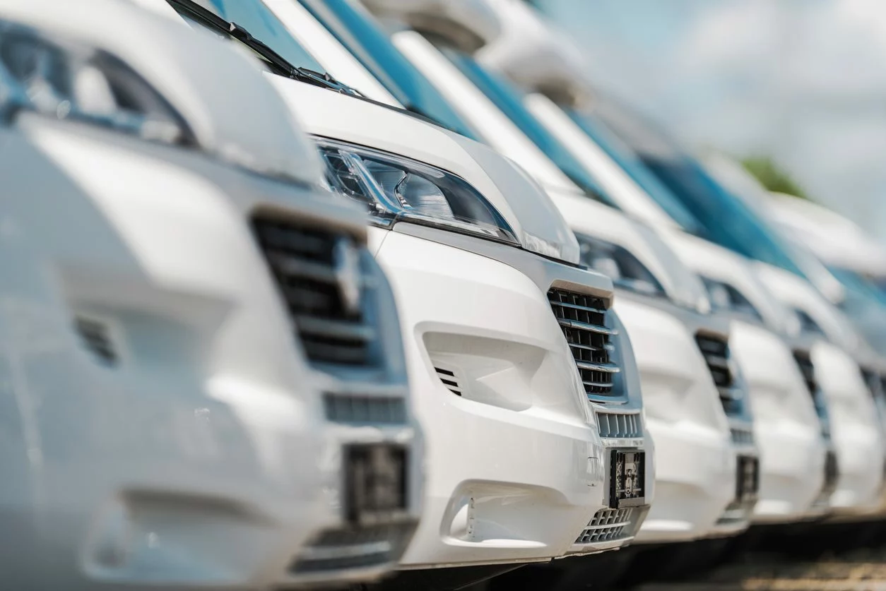 A row of white camper vans for sale in a dealership lot.