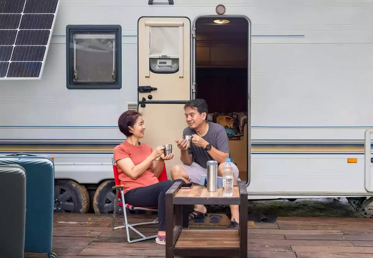 A couple sitting and relaxing outside of their RV.