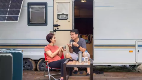 A couple sitting and relaxing outside of their RV.