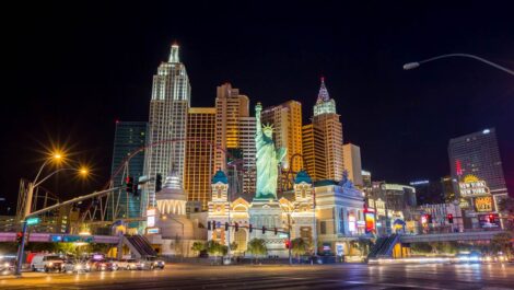 The Las Vegas Strip lit up at night, with buildings in various architectural styles and a smaller scaled version of the Statue of Liberty.