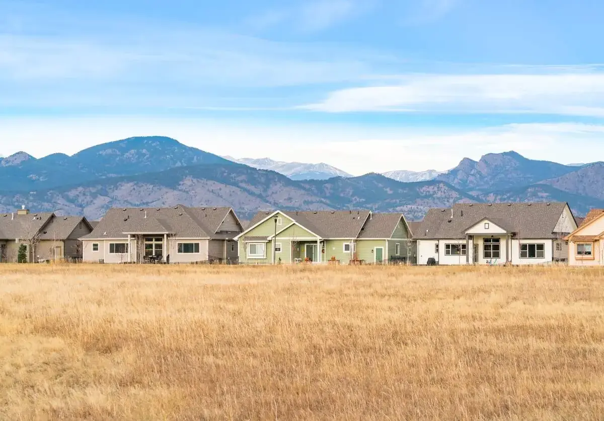 A row of houses in Loveland, CO, with a grass field and scenic Rocky Mountains.