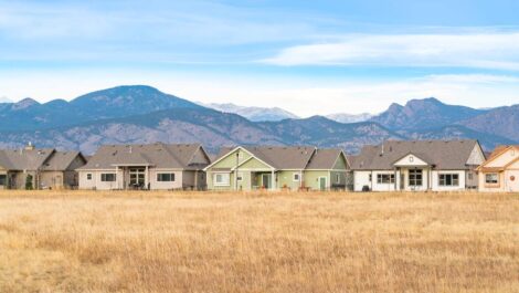 A row of houses in Loveland, CO, with a grass field and scenic Rocky Mountains.