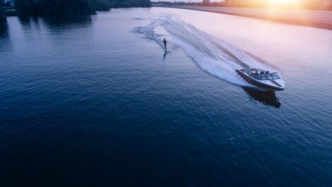 A man water skiing on a lake behind a boat at sunset.