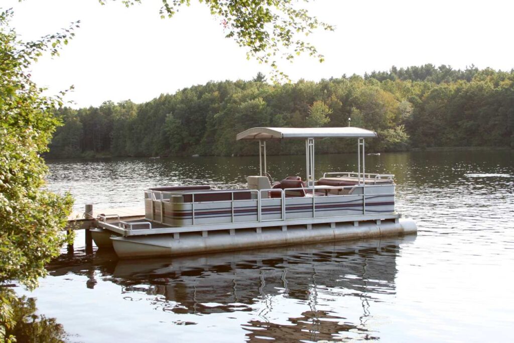 A pontoon boat docked by the banks of a river.