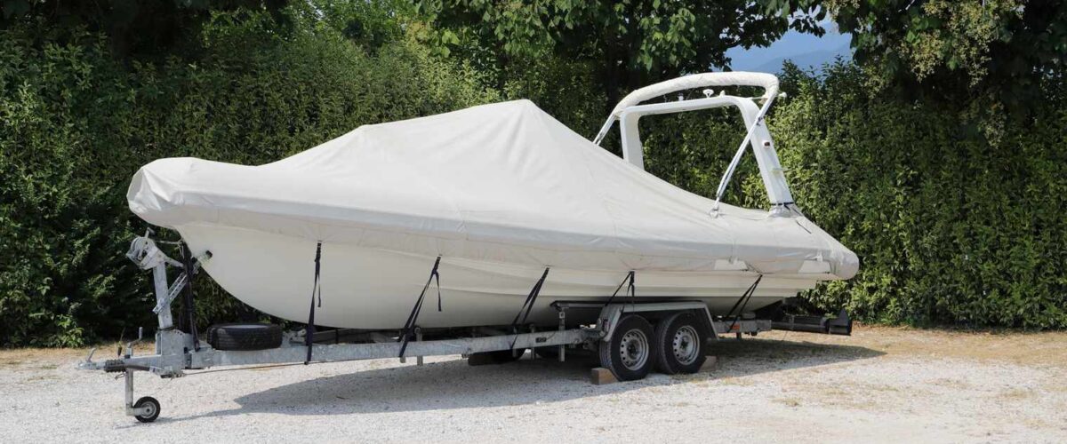 A trailer with a boat on top and covered with a white cover.