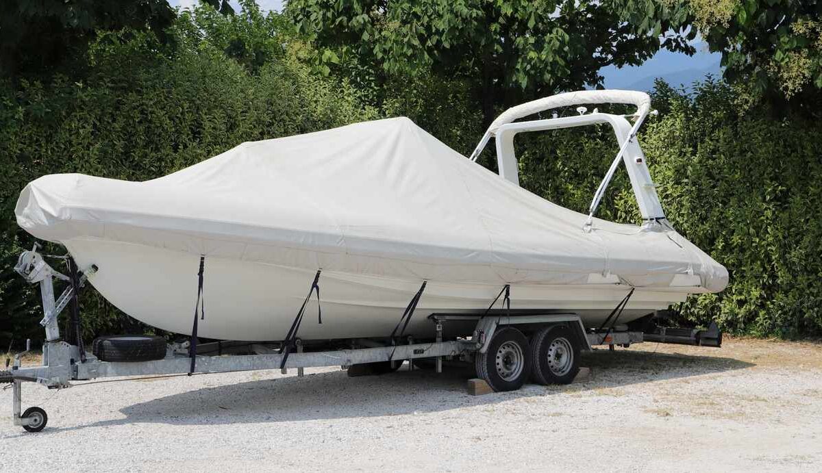 A trailer with a boat on top and covered with a white cover.
